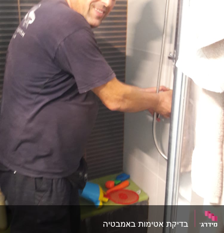 אדם עובד על תיקון מקלחת עם כלים